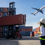 Logistics supervisor monitoring container loading with airplane flying overhead